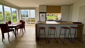 Cozinha moderna com ilha central, banquetas de bar e área de jantar com mesa e cadeiras.