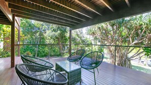 A covered outdoor area with a wooden deck, metal-framed chairs, and a glass table. - Pacifica 2 - Brooms Head (Brooms Head)