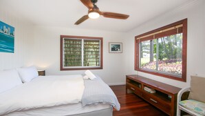 A bedroom with a bed, a ceiling fan, a window with blinds, a bedside table, and a chair. - Pacifica 2 - Brooms Head (Brooms Head)