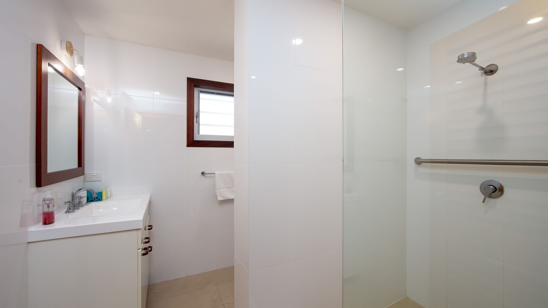Een moderne badkamer met een witte wastafel, spiegel en douche.