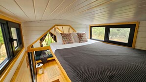 Un dormitorio con literas, una ventana con vistas a árboles y un techo de madera.