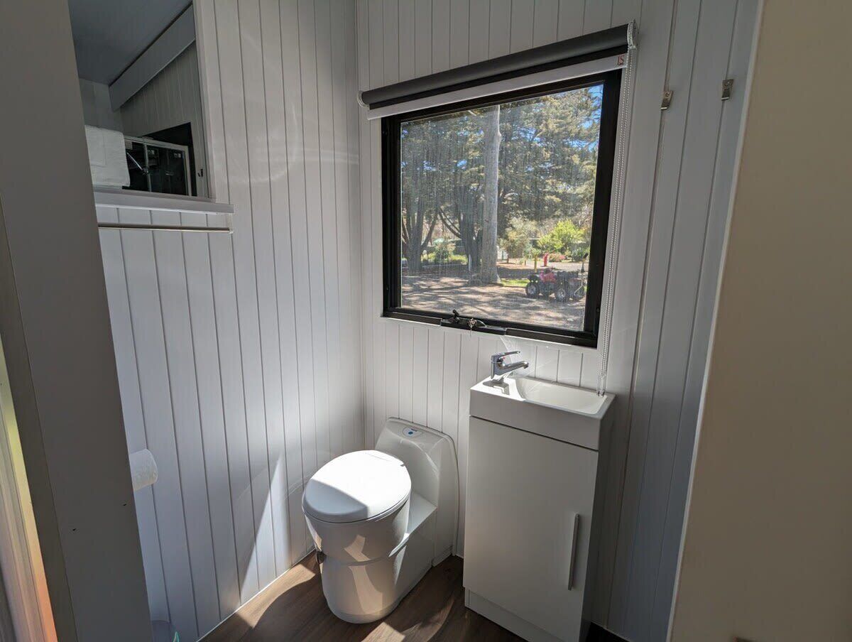 Une petite salle de bain comprenant des toilettes, un lavabo et une fenêtre.