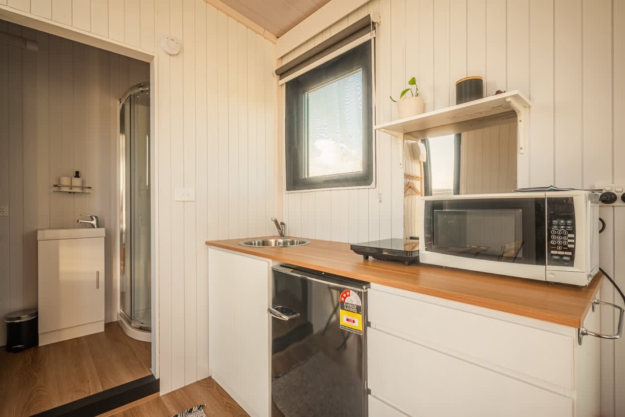 Una cocina compacta con microondas, lavabo y un refrigerador pequeño.