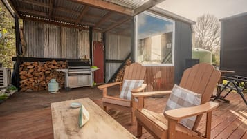Una terraza al aire libre con una parrilla, sillas y una mesa.