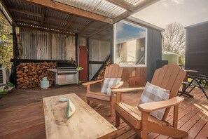 Eine Terrasse im Freien mit Grill, Stühlen und Tisch.