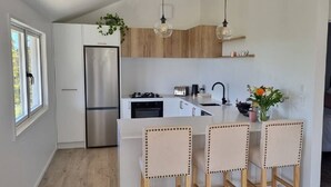 A modern kitchen with a central island, stainless steel appliances, and pendant lighting. - Huntsbury Hideaway, Cottage with amazing views (Christchurch)