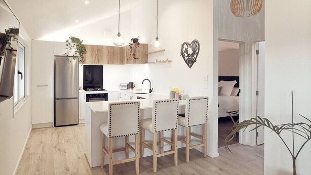 A modern kitchen with a central island, wooden chairs, and pendant lighting. - Huntsbury Hideaway, Cottage with amazing views (Christchurch)