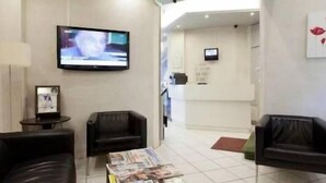 Una zona d'espera moderna amb sofàs de pell, una televisió de pantalla plana i una taquilla.
