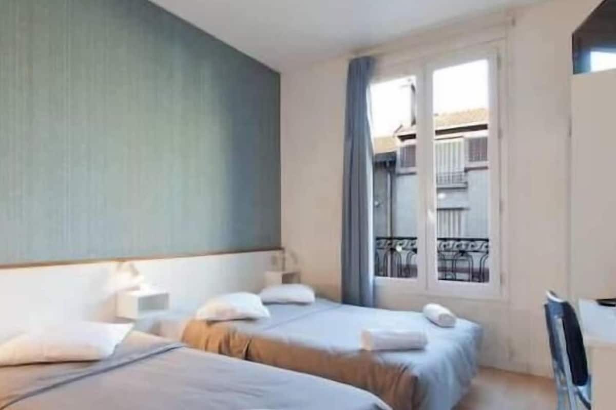 A hotel room with two beds, a window with a view of the outside, and a balcony.