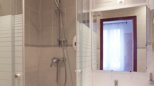 A modern bathroom with a glass-enclosed shower, a pedestal sink, and a mirror above the sink. - Hotel Victor Hugo (Clamart)