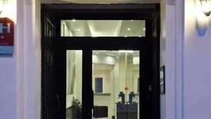 A hotel entrance with a glass door, a reception desk, and a visible interior space with a counter and chairs. - Hotel Victor Hugo (Clamart)