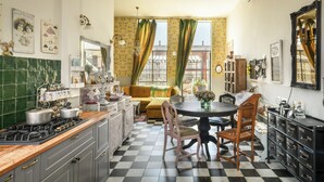 Une cuisine avec un carrelage à motifs, une table à manger avec des chaises, un canapé et une fenêtre avec des rideaux.