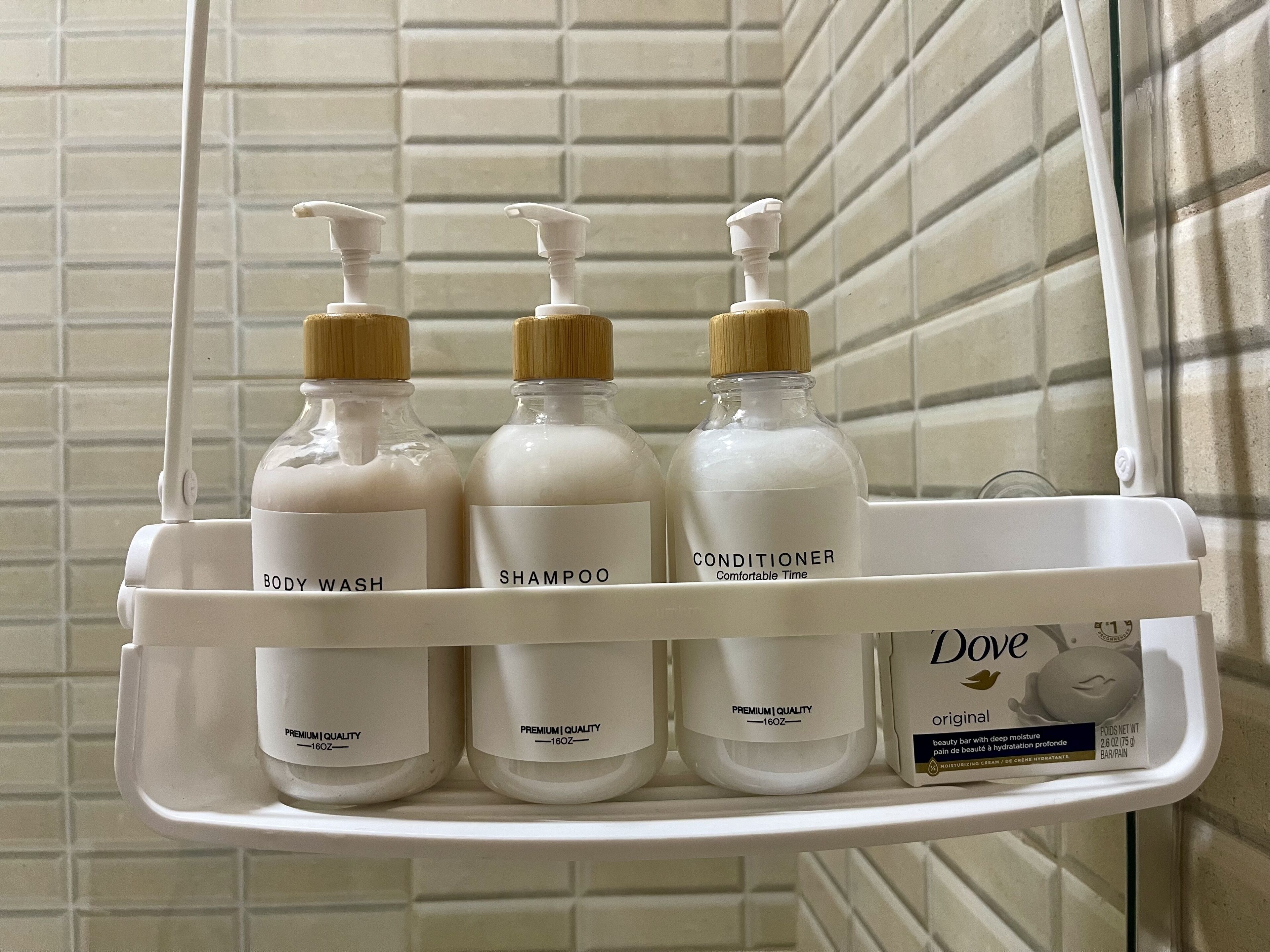A bathroom shelf with three bottles of Dove body wash, shampoo, and conditioner.