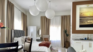 Una habitación de hotel moderna con cama, sofá, zona de comedor y kitchenette.