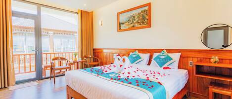 A hotel room with a bed, a balcony, a painting, and a wooden headboard.