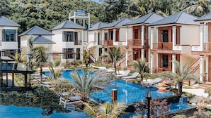 Ein Resort mit mehreren Villen, einem zentral gelegenen Swimmingpool und üppiger Bepflanzung.
