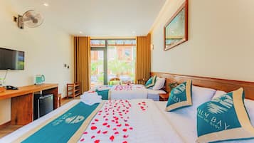 A hotel room with two beds, a desk, a television, and a large window with curtains.