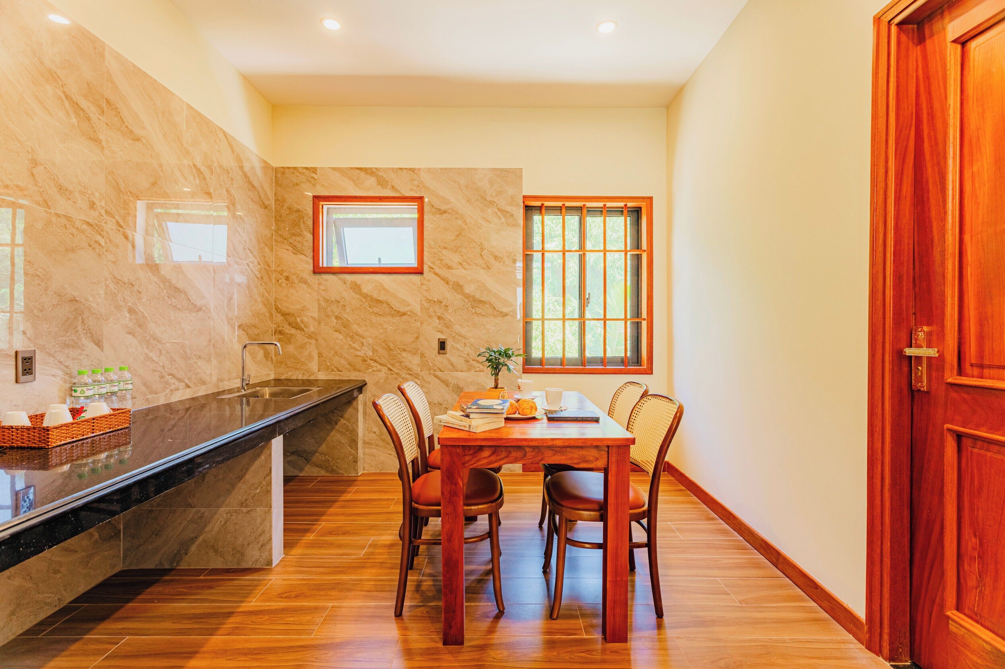 Comedor con pared de mármol, mesa de madera y sillas.