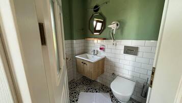 A compact bathroom with a wooden cabinet, a white sink, a toilet, and a mirror.