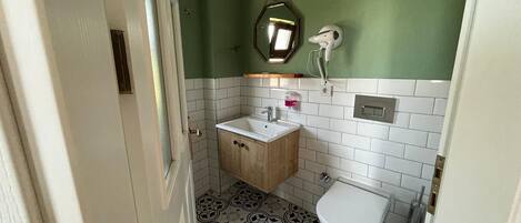 A compact bathroom with a wooden cabinet, a white sink, a toilet, and a mirror.