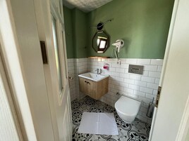 Un baño pequeño con un mueble de madera, un lavamanos blanco, un inodoro y un espejo.