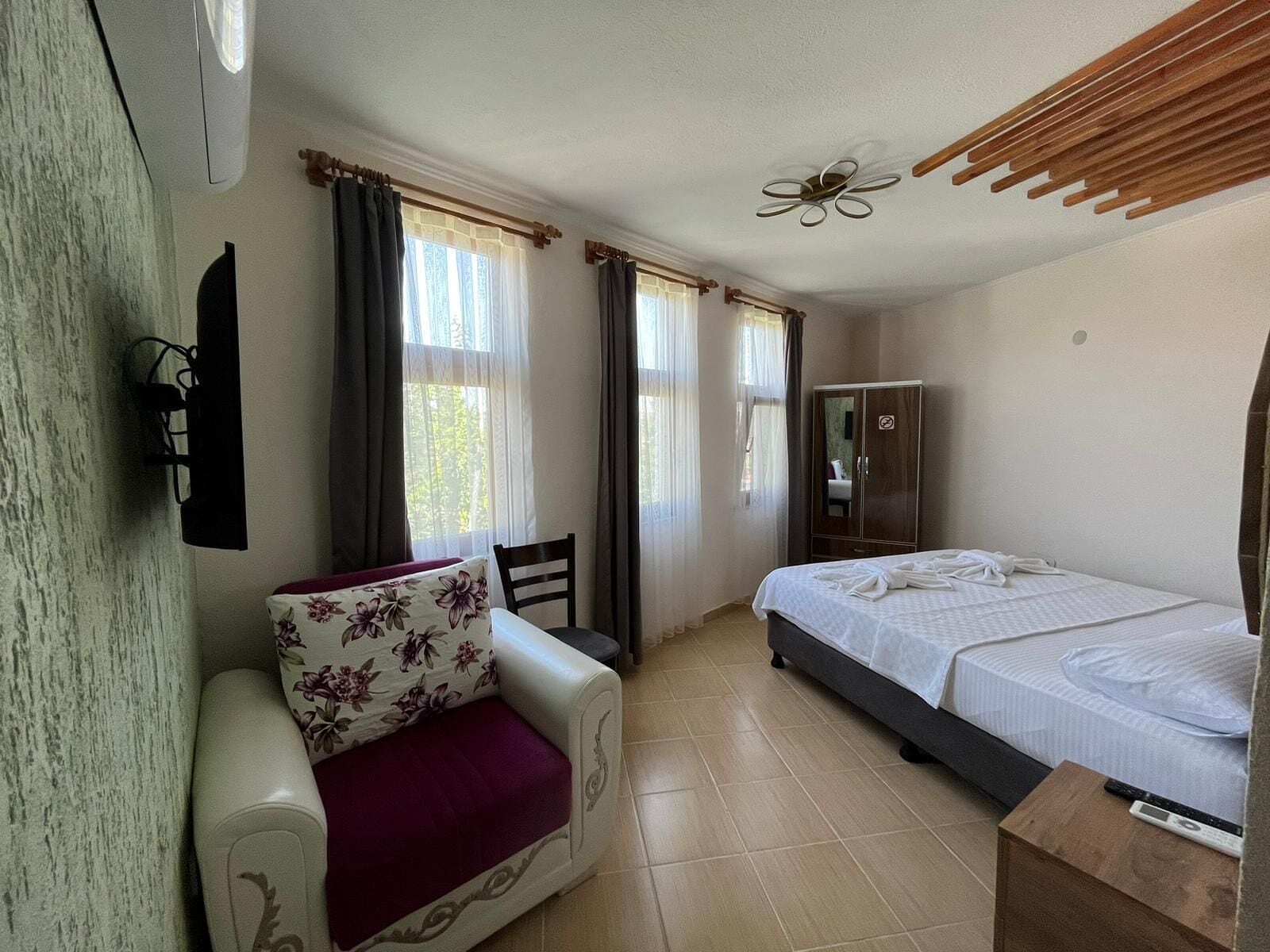 Ein Hotelzimmer mit Bett, Schlafsofa, Kleiderschrank und Deckenventilator.