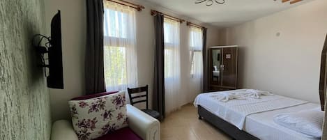 Ein Hotelzimmer mit Bett, Schlafsofa, Kleiderschrank und Deckenventilator.