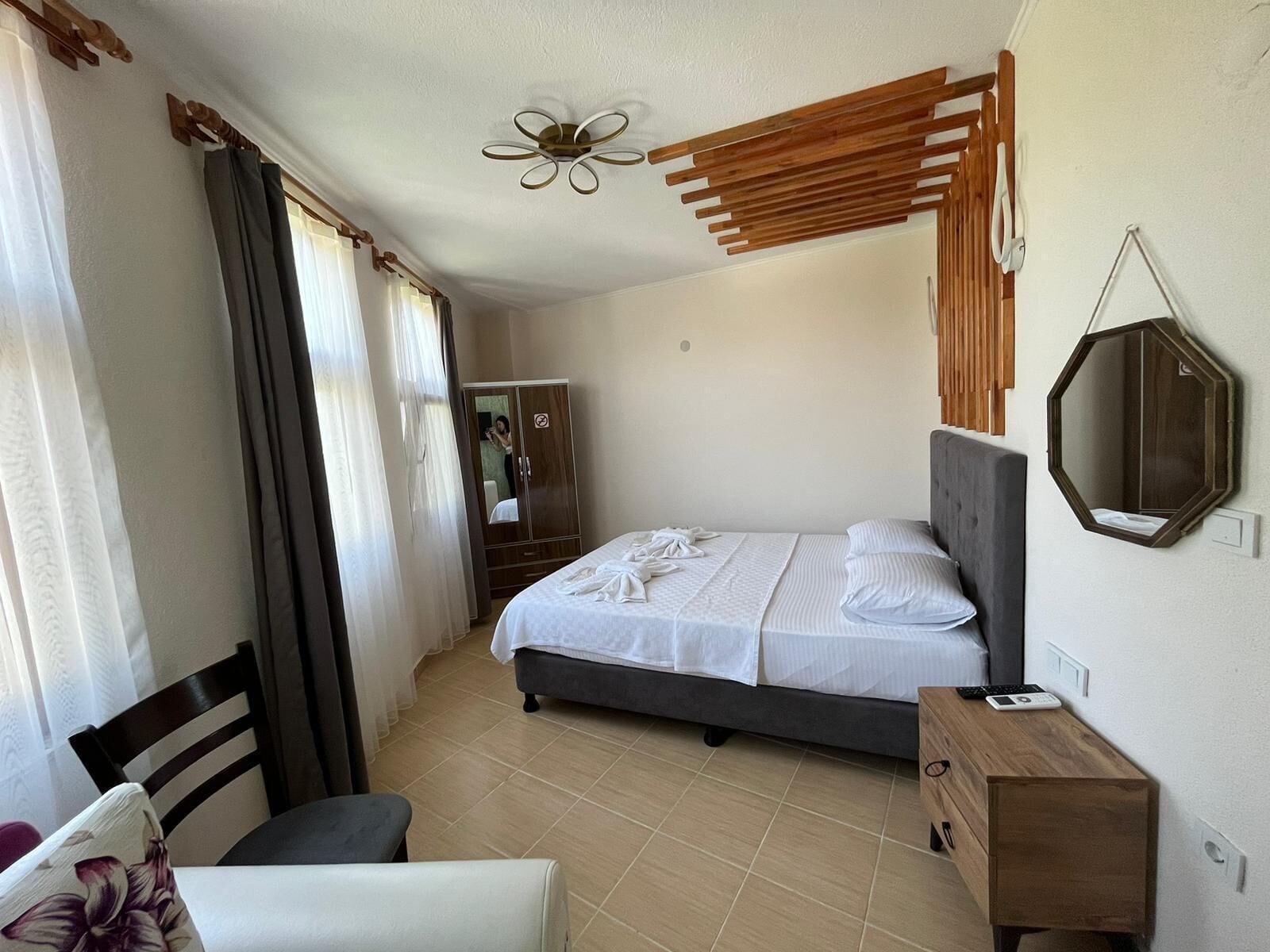 Une chambre à coucher comprenant un lit, une tête de lit en bois, une armoire en bois, un miroir et une chaise.