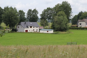 A house with a red door and a small shed in a grassy field.