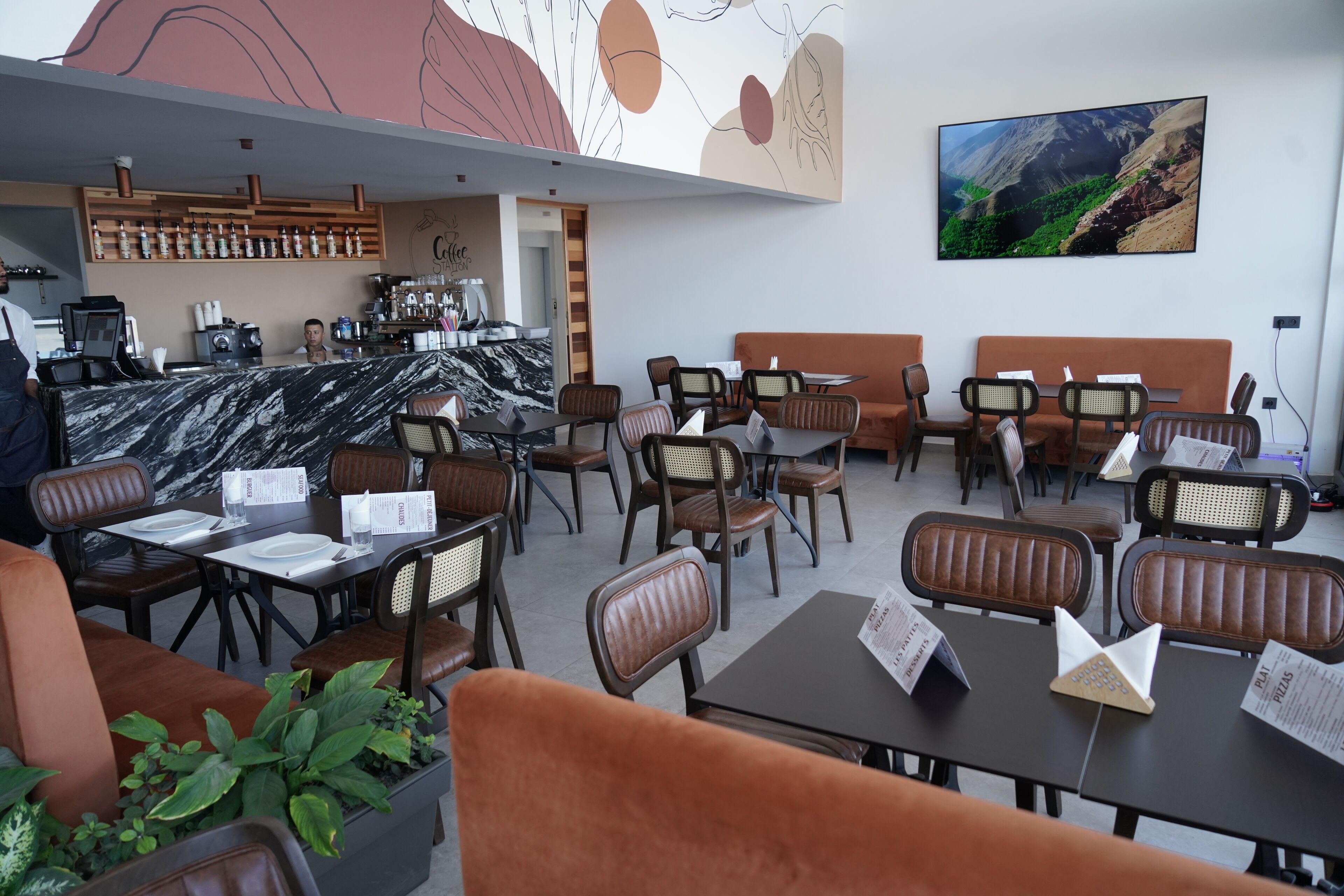A restaurant with marble-topped tables, brown cushioned booths, and a coffee bar.