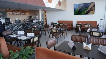 A restaurant with marble-topped tables, brown cushioned booths, and a coffee bar.
