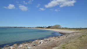 Eine Küstenlandschaft mit felsiger Küste, ruhigem Wasser und wolkenlosem Himmel.