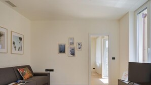 A modern living room with a sofa, a flat-screen TV, and framed artwork on the walls. - Riviera Flavour Apartments by Wonderful Italy - Ginestra (Santa Margherita Ligure)