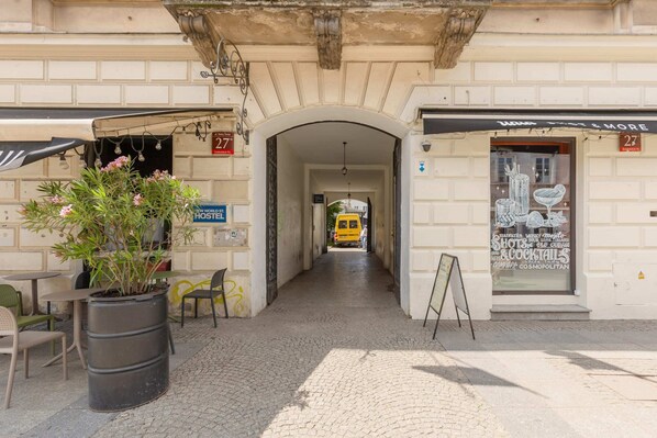 Experience the vibrant atmosphere of this urban street, home to a bustling café and a historic building with a classic arched doorway.