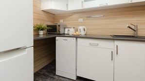 A modern kitchen with white cabinetry, a microwave, a coffee maker, and a dishwasher.