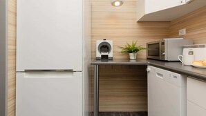 A compact kitchen with a refrigerator, microwave, and dishwasher.