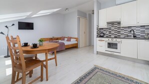 A modern apartment with a dining area, a bed, a kitchenette, and a TV mounted on the wall. - Modern Studio in the heart of Kazimierz | Close to Attractions (Kraków)