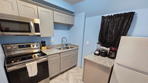 A compact kitchen with a microwave, stove, sink, and refrigerator. - Private Studio Apartment In Lewes (Lewes)