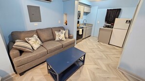 A compact living space with a sofa, a coffee table, a kitchenette, and a small dining area. - Private Studio Apartment In Lewes (Lewes)