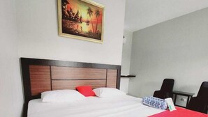 Ein Hotelzimmer mit einem großen Bett, einem Bild an der Wand und einem Schreibtisch mit Stuhl.