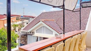Ein Balkon mit Holztisch und -stühlen, der auf ein Wohngebiet mit Ziegeldächern blickt.