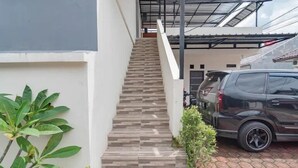 Eine Treppe führt zu einem überdachten Bereich, wo ein Auto geparkt ist.