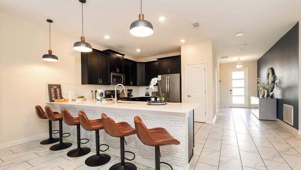 A modern kitchen with a central island, bar stools, pendant lighting, and a dark-colored backsplash. - Spacious Davenport Villa, Sleeps 21, Pool & Fun (Davenport)