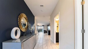 A modern hallway with a dark wall, a gold-framed mirror, and a white vase with flowers. - Spacious Davenport Villa, Sleeps 21, Pool & Fun (Davenport)
