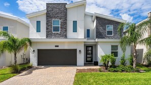 A modern two-story house with a garage, a stone accent wall, and a well-maintained lawn with small trees. - Spacious Davenport Villa, Sleeps 21, Pool & Fun (Davenport)