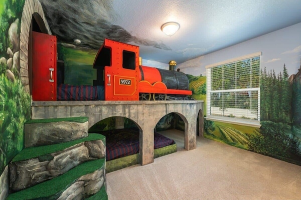 All aboard the adventure express! This train-themed room offers a magical escape for kids with bunk beds and scenic murals.