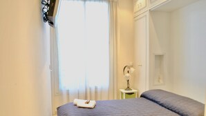 A bedroom with a bed, a nightstand, a lamp, and a window with curtains. - LON5218 (Cannes)