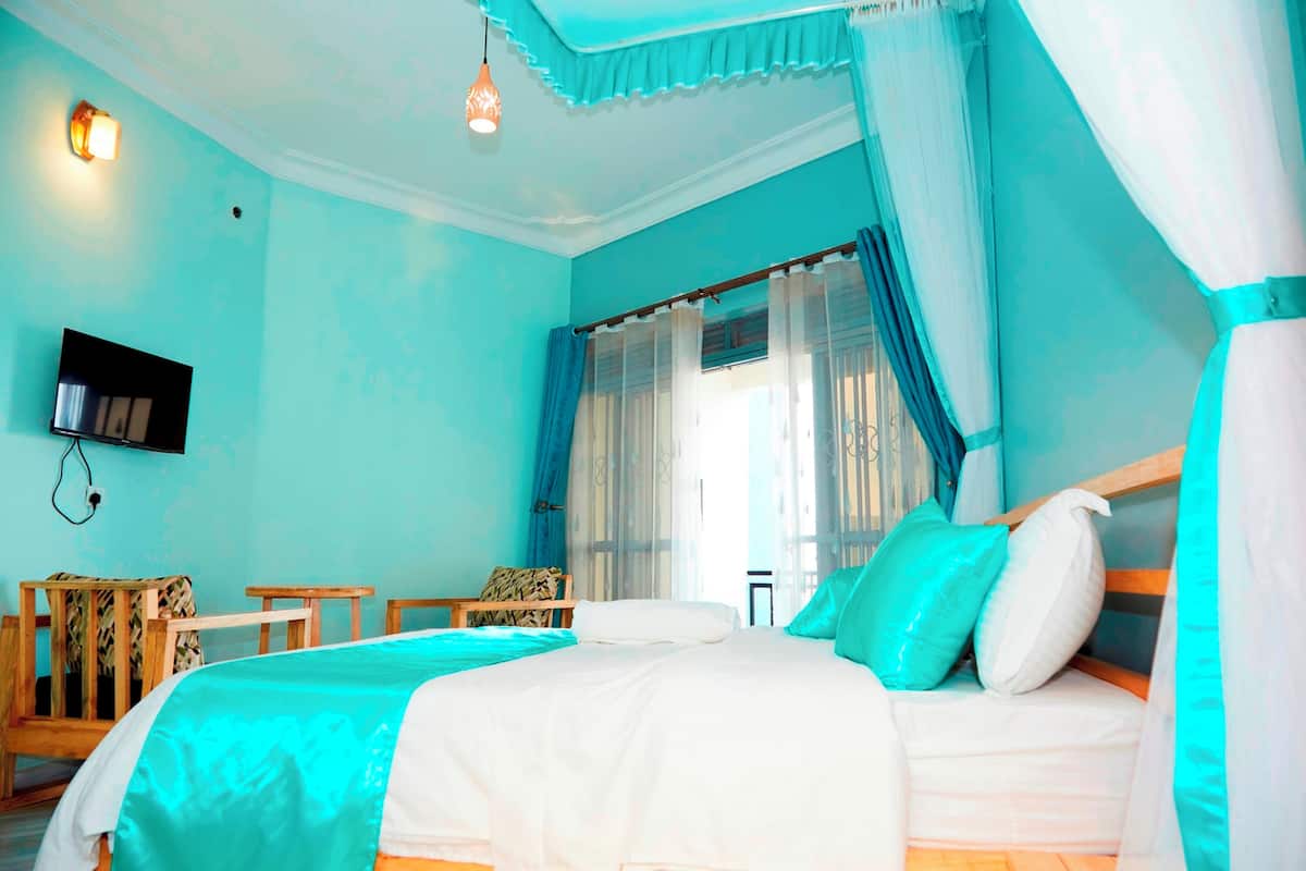 A bedroom with a bed, a TV, a small table, and a chair.