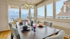 Comedor con una mesa dispuesta para seis personas, ventanas amplias con vista a la montaña y un balcón visible.