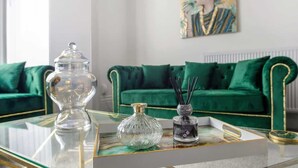 Ein modernes Wohnzimmer mit Glastisch, Sofa in Grün und einem Gemälde an der Wand.
